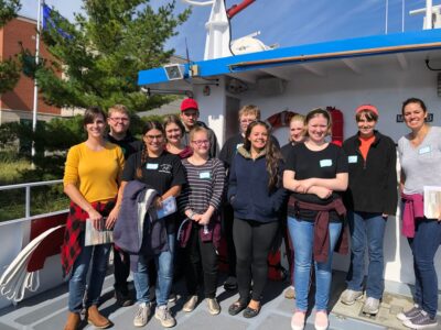 A group of students smiling and posing for a photo on a boat